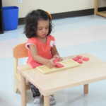 A little girl playing with small red boards