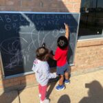 Two children writing on a black board (150x150)