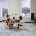 Two little girls playing together in their classroom seat (150x150)