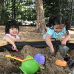 Two little girls holding shovels in the sandbox (150x150)