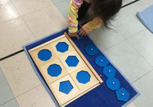A little girl playing with a geometric cabinet