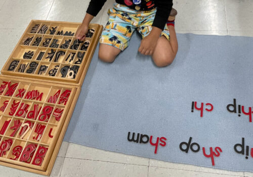 A boy making a sentence using wooden letters