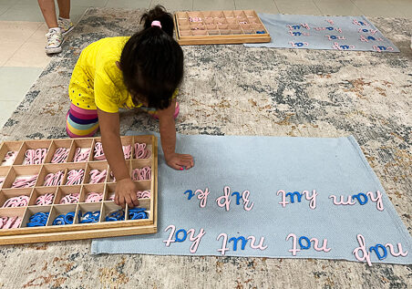 A girl making a sentence using wooden letters