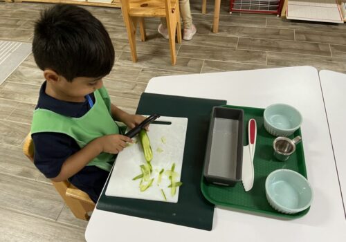 A little boy peeling cucumbers